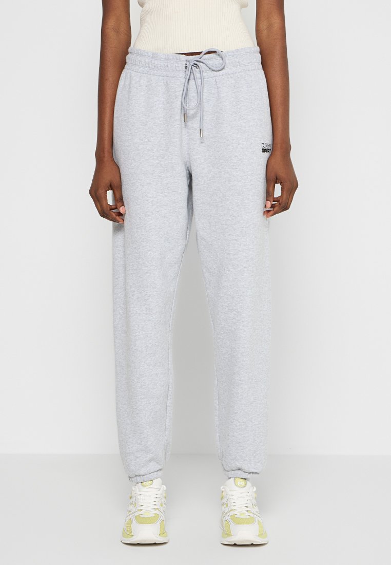 Szare dresy wykonane z miękkiego materiału, z elastycznym paskiem w talii i mankietami. Małe czarne logo na biodrze. Prosty krój.