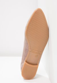 Semelle d’une chaussure en daim taupe à bout pointu avec semelle en caoutchouc beige, motif antidérapant texturé, nom de la marque Tamaris et taille 37 embossée sur la semelle.