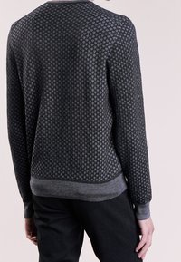 Pull en tricot gris foncé avec un motif texturé en losanges, col rond, poignets et ourlet côtelés, et accents gris contrastants.