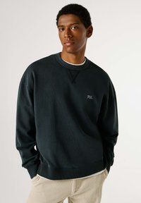 Felpa in cotone verde scuro con texture a coste e scollatura rotonda. Logo ricamato "PJL" sul petto. Tessuto morbido, vestibilità casual.