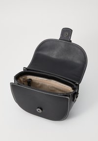 Bolso de cuero negro con tapa y costuras blancas. El interior cuenta con un forro con estampado y un compartimento con cremallera para un almacenamiento seguro.