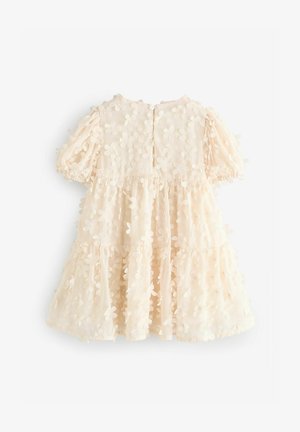 Cvečna obleka iz mehke bež tkanine, ki se ponaša s plastnim dizajnom, kratkimi napihnjenimi rokavi in gumbom na hrbtni strani. Po celotni obleki so prisotni teksturirani cvetlični poudarki.