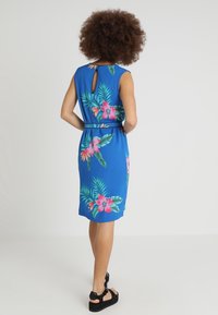 Blå klänning med blommönster, som har rosa blommor och gröna blad. Rund hals, figurnära design och en nyckelhålsdetalj bak.