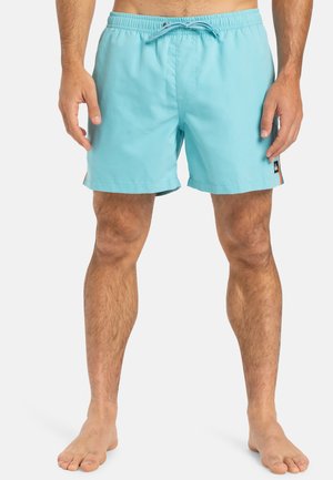 Helle blaue Badeshorts aus schnelltrocknendem Material, mit einem elastischen Bund mit Kordelzug und seitlichen Einschubtaschen.