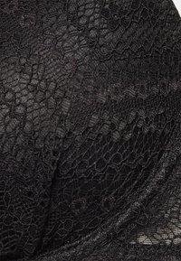 Tissu en dentelle noire avec un motif floral et des textures variées, mettant en avant des détails complexes et une apparence lisse, légèrement transparente.