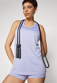 Light purple tank top with rounded neckline and Nike logo, paired with matching shorts. Black jump rope hangs around the neck.