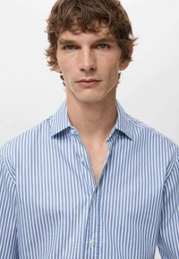 Camicia a righe blu e bianche con colletto button-down, tessuto morbido e design semplice. Presenta una vestibilità regolare e una texture liscia.