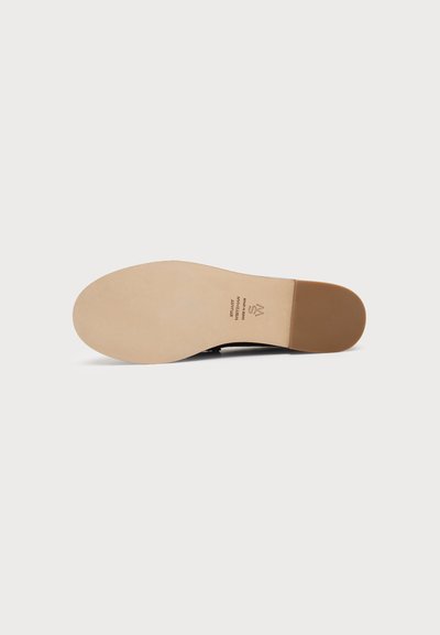 Semelle de chaussure habillée en cuir beige avec un talon brun plus foncé, vue de dessous sur fond blanc uni. Aucun motif de semelle visible.