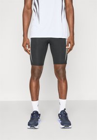 Black athletic shorts with white side stripes, paired with a white patterned shirt, white socks, and navy running shoes.