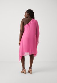 Asymmetrical pink chiffon dress with a single shoulder design and flowing hem, paired with nude block-heeled sandals.