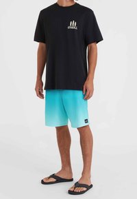 Sort kortærmet t-shirt med et beige surfbræt grafik, parret med gradient aqua badeshorts og sorte flip-flops.