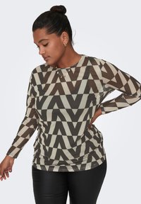 Top a maniche lunghe in tessuto trasparente marrone con motivo geometrico a zigzag in crema. Collo rotondo e maniche aderenti. Abbinato a leggings neri.