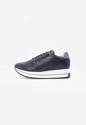 Black leather sneaker featuring a white sole and prominent logo on the side. Rounded toe and lace-up design with textured accents.