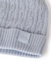 Berretto lavorato a maglia azzurro chiaro con motivo a trecce, caratterizzato da un polsino a coste e una piccola etichetta con il disegno di un coniglio. Tessuto morbido e vestibilità flessibile.