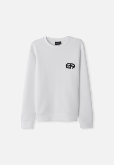 Sudadera blanca de manga larga, con cuello redondo y un logo bordado en negro en el lado izquierdo del pecho. Textura suave, diseño minimalista.
