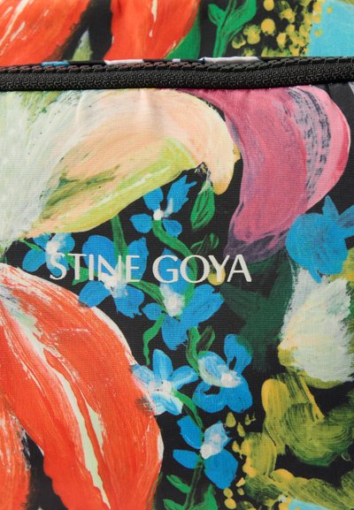 Krāsains audums ar abstraktiem ziedu rakstiem sarkanā, rozā, dzeltenā un zilā krāsā uz melna fona, ar brenda nosaukumu "STINE GOYA" drukātu baltā krāsā.