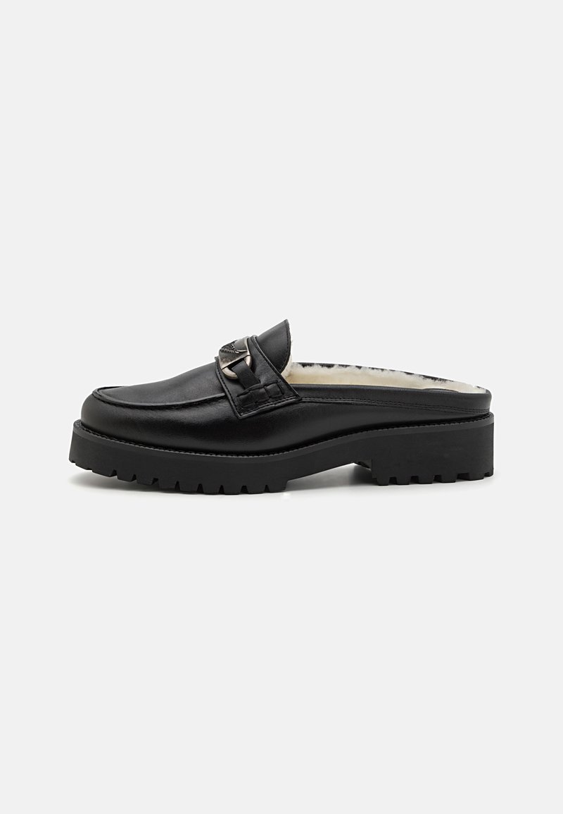 Black leather slip-on shoe with a textured surface, thick sole, and a decorative metal buckle. Inside features soft lining for comfort.