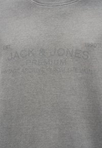 Γκρι φούτερ με λαιμόκοψη crew, απαλό ύφασμα και τυπωμένες λεπτομέρειες με λογότυπο σε πιο σκούρο γκρι, συμπεριλαμβανομένων των "JACK & JONES" και "EST 1990".