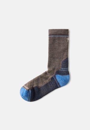 Calzini a coste marroni e blu navy con accenti blu sul tallone e sulle punte, caratterizzati da un tessuto testurizzato e motivi geometrici in tonalità più scure.