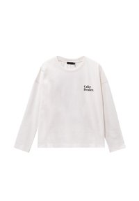 Camisa blanca de manga larga en suave algodón con cuello redondo y el texto "Cake Dealer" impreso en negro en el pecho.