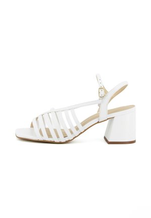 Sandalo aperto in pelle bianca con più cinturini, fibbia regolabile alla caviglia e tacco a blocco su sfondo bianco.