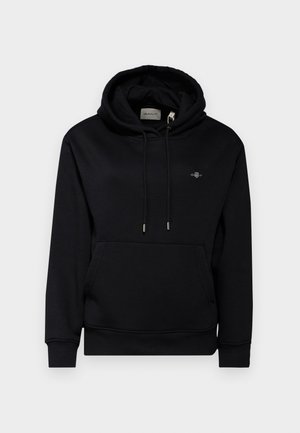 Čierna mikina s kapucňou, predným vreckom, šnúrkami a mäkkou tkaninou. Má malú vyšívanú nášivku na hrudi a rebrované manžety.