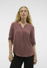 Blusa a V con taglio morbido in rosa tenue, caratterizzata da un tessuto testurizzato, maniche arrotolabili con dettagli in bottone e orlo curvo.