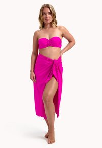Top de bikini rosa tipo bandeau con centro fruncido y falda larga a juego con una alta abertura y dobladillo con volantes, diseñado en una tela ligera.