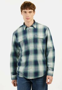 Langdurig gestreept shirt met lange mouwen in tinten blauw en groen, voorzien van een knoop-onder hals, twee borstzakken en een relaxed fit.