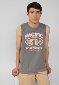 Szara koszulka bez rękawów z dużym różowym napisem "PACIFIC CUSTOMS BOARDS&KITS VENICE PIER, L.A." Gładki materiał, okrągły dekolt.