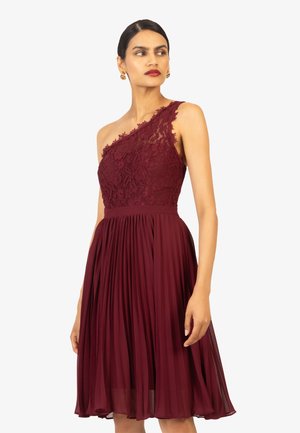Bordeaux jurk met een een-schouder kanten bustier en geplisseerde chiffon rok. Heeft delicate kanten details en een strakke taille.