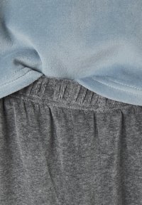 Light blue fleece fabric overlapping dark gray elastic waistband fabric with visible stitching and soft texture details.