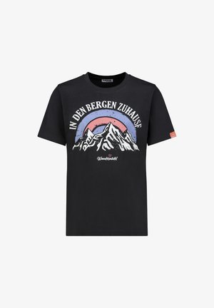 Black t-shirt with white mountain illustration, red and blue semi-circle background, and German text "IN DEN BERGEN ZUHAUSE" above.