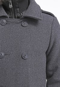 Szary płaszcz typu peacoat z mieszanki wełny, z dwurzędowym zapięciem, dużymi czarnymi guzikami oraz wysokim kołnierzem z prążkowanymi akcentami przy szyi.