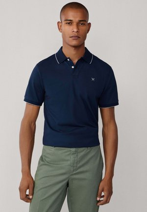 Polo azul marino de ajuste slim, con mangas cortas y costuras en contraste blanco en el cuello y los puños. Presenta un logo sutil en el pecho.