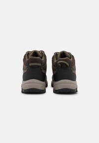 Zapatos de senderismo marrones y negros con una parte superior de malla texturizada y talón reforzado. Suelas de goma gruesas proporcionan tracción y soporte.