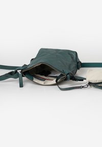 Borsa a tracolla in pelle di colore teal con apertura superiore zip, che rivela una fodera interna a righe e una pochette rimovibile, dotata di tracolla regolabile.