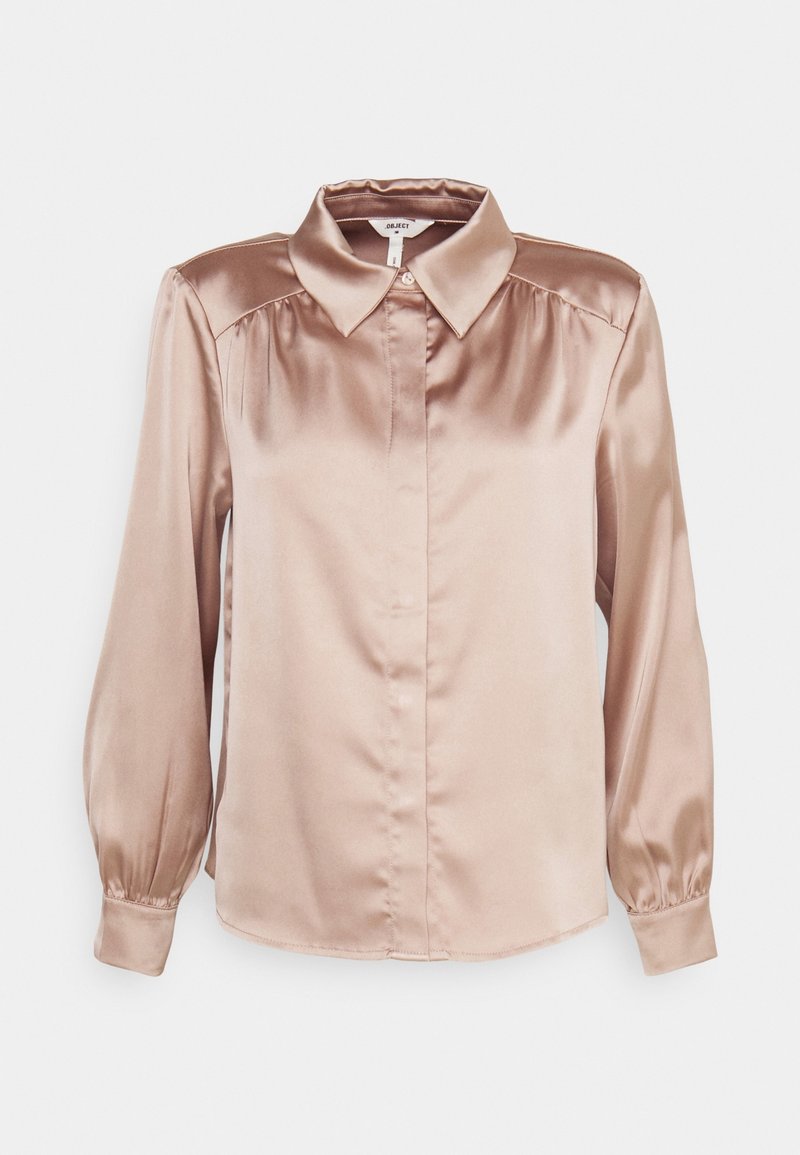 Blouse légère couleur marron clair, semblable à de la soie, avec un col classique, une fermeture à boutons sur le devant et des manches ballons. Texture lisse avec un éclat subtil.