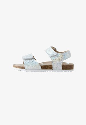 Glitrende hvide sandaler med to justerbare velcrobånd, brun korksål og hvid struktureret ydersål. Åben tå-design for åndbarhed.