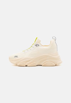 Chunky white sneakers with mesh upper, lime green accents, and thick rubber sole featuring a textured grip pattern and logo detail.