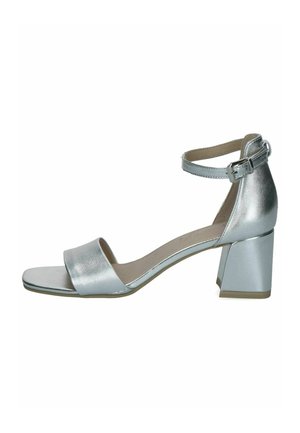 Sølv åben tå sandal med blokhæl og ankelrem med lille spænde, vist mod en hvid baggrund.