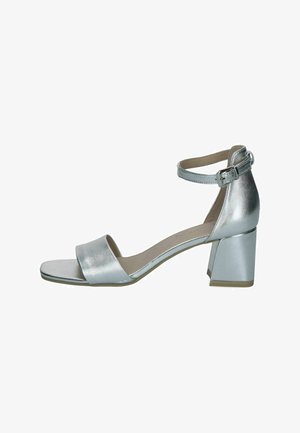 Stříbrná sandálová obuv s otevřenou špičkou, blokovým podpatkem a páskem kolem kotníku s malou přezkou, zobrazena na bílém pozadí.