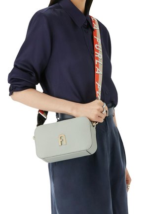 Helles grünes Lederhandtasche mit rechteckiger Form, goldenen Beschlägen und einem gemusterten Tragegurt mit "Furla"-Text in Rot und Creme.