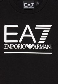 Černé tričko s velkým bílým logem EA7 a textem "EMPORIO ARMANI". Materiál je hladký s klasickým designem kulatého výstřihu.