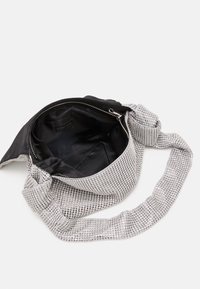 Borsa a tracolla in ecopelle argentata con interno in tessuto nero; presenta una chiusura con zip e un design della tracolla annodata.
