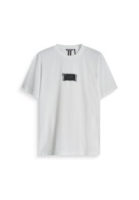 Camiseta de algodón blanca con cuello redondo y mangas cortas, con un parche de logo rectangular negro que dice "I AM".