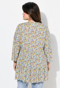 Blomstret kjole med en lilac baggrund, prydet med gule, blå og lilla blomster. Trekvartærmer og en samlet, rynket kant.