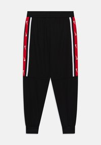 Melnas sporta bikses ar sarkanām sānu paneļu joslām, uz kurām ir baltas svītras un Nike logotipi. Elastīga jostasvieta un ribotie potīšu velcro, lai nodrošinātu labu pielāgošanu.