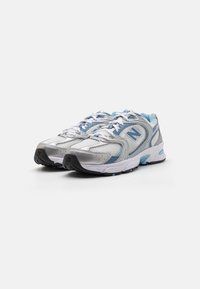 Scarpe da allenamento argento e blu con texture in rete, design con lacci e suole in gomma. Logo 'N' ben visibile sul lato e collo imbottito.