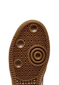 Sole in gomma marrone con un motivo geometrico a diamante, accenti circolari e superficie texturizzata per una migliore aderenza. La forma della suola segue il design standard delle calzature.